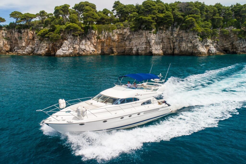 Luxury private yacht cruising along the Adriatic Sea near Dubrovnik cliffs on a sunny day