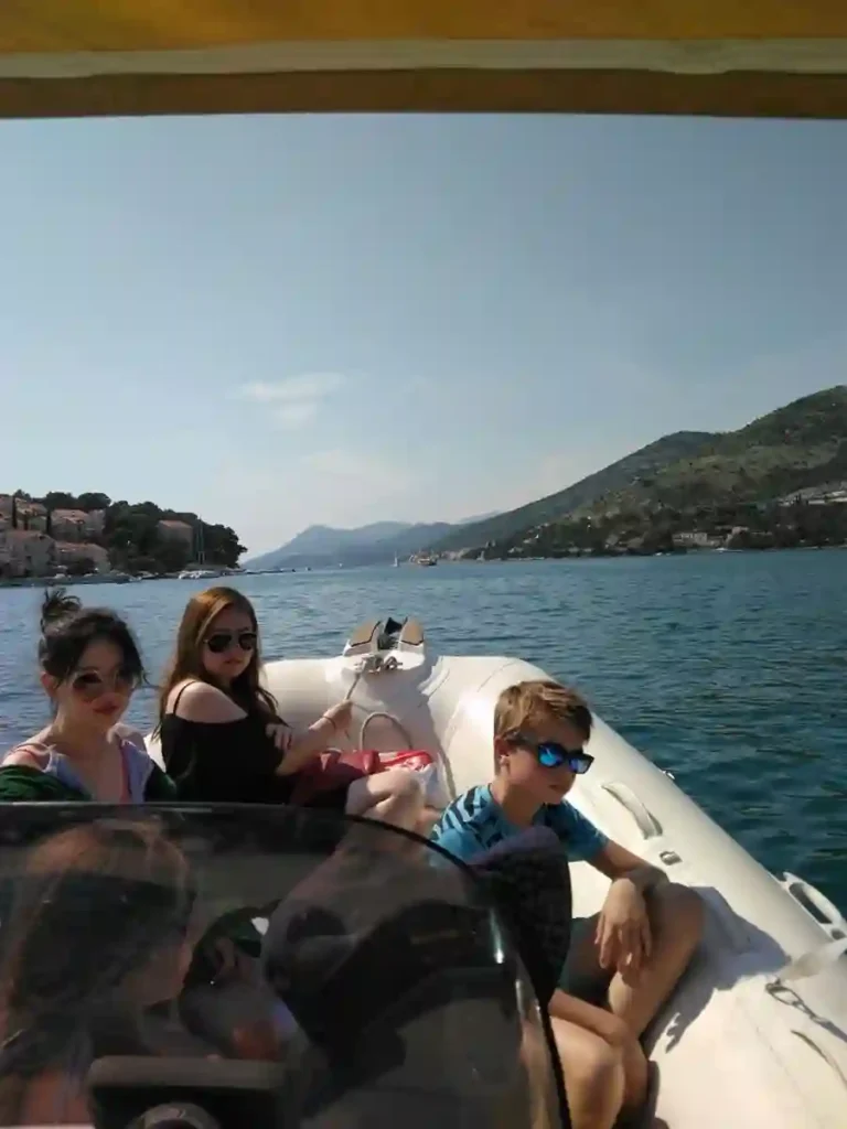 Family enjoying a relaxing private boat ride near Dubrovnik on a sunny day with coastal views in the background